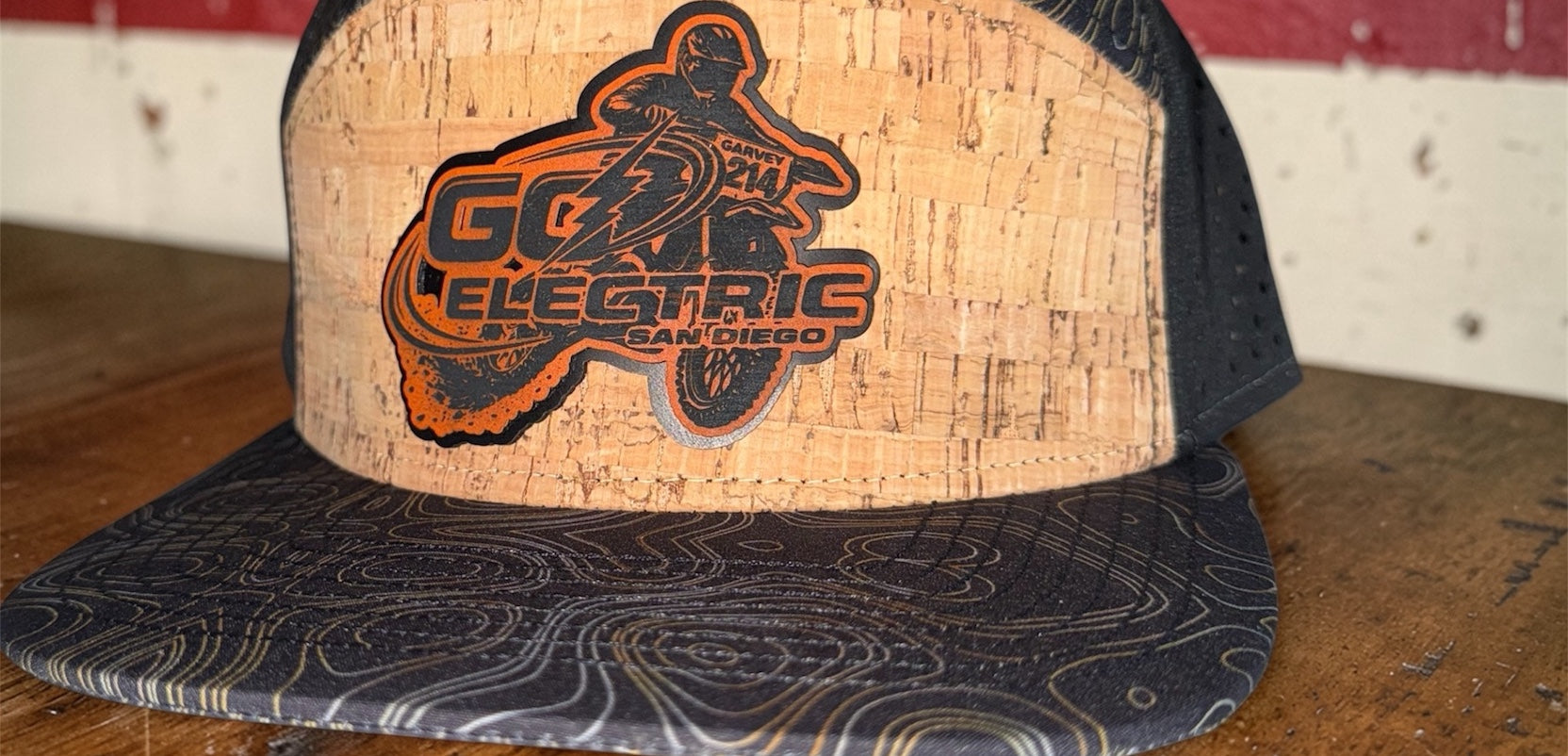 Custom cap with cork front panel featuring 'Go Electric' logo on a wooden surface