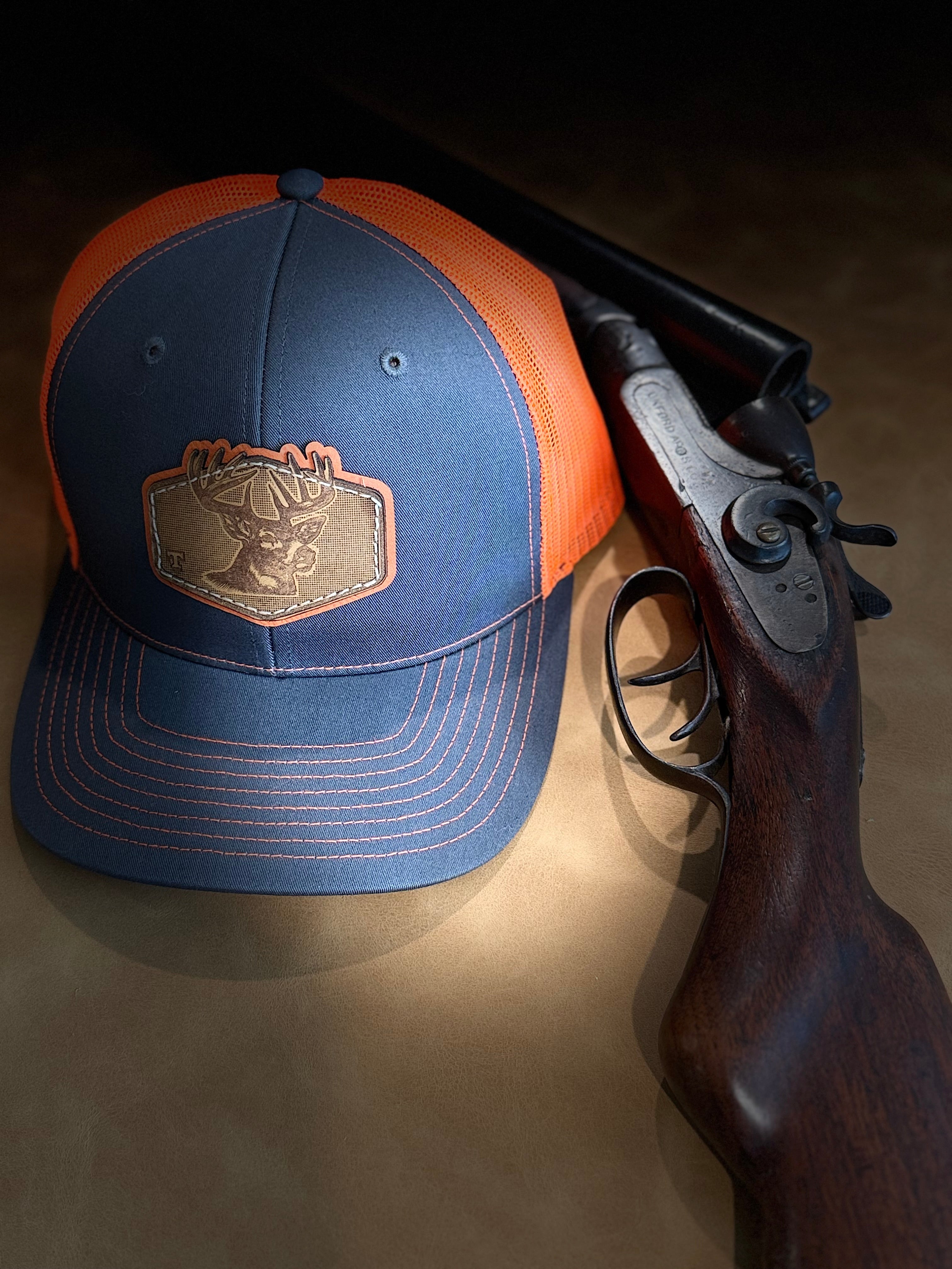 Blue and orange cap with a logo next to a shotgun