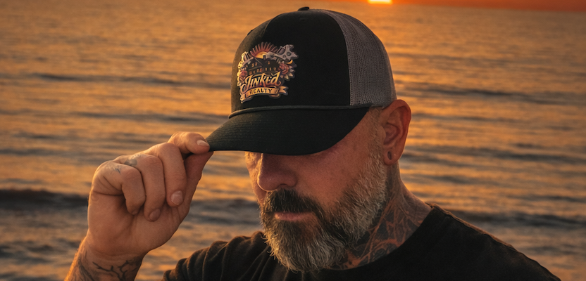 Man wearing a custom-made cap with a sunset over water in the background