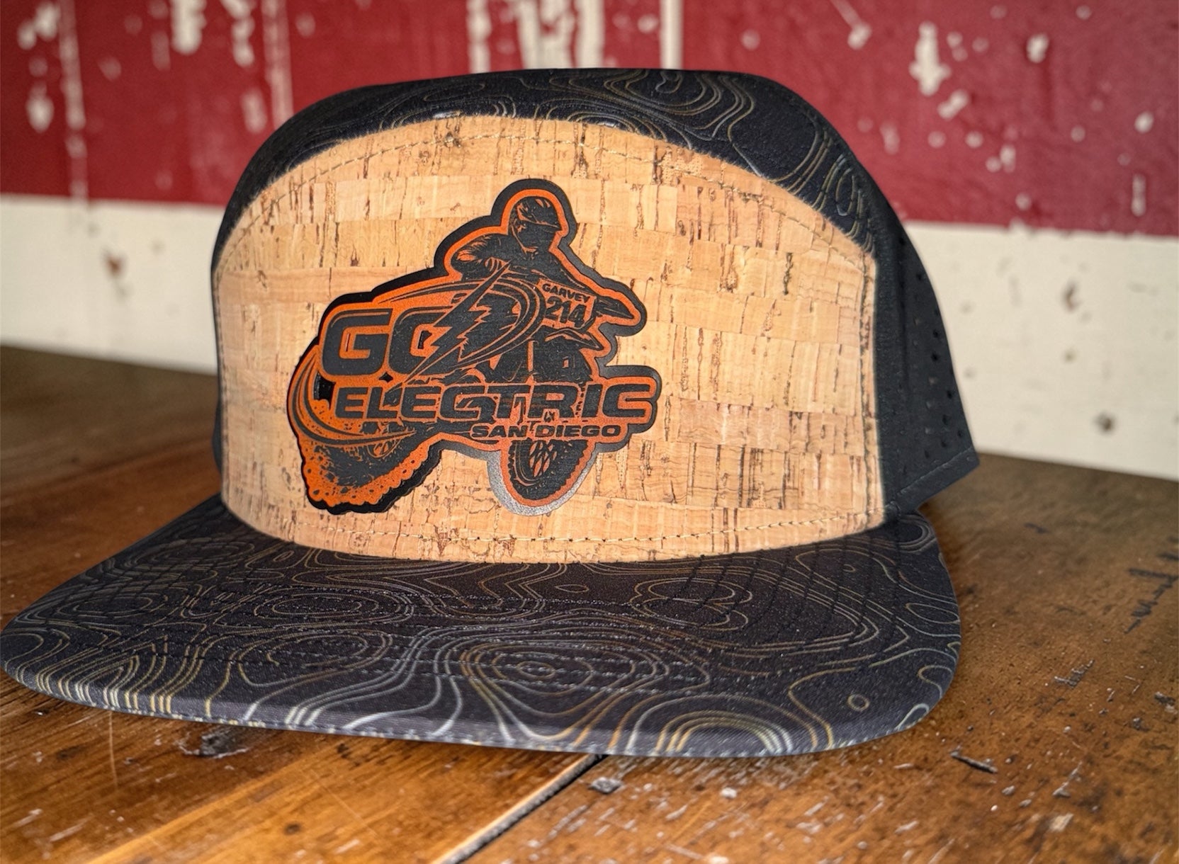 Custom cap with cork front panel featuring 'Go Electric' logo on a wooden surface