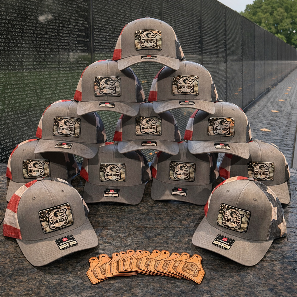Stack of gray hats with patches in front of a memorial wall