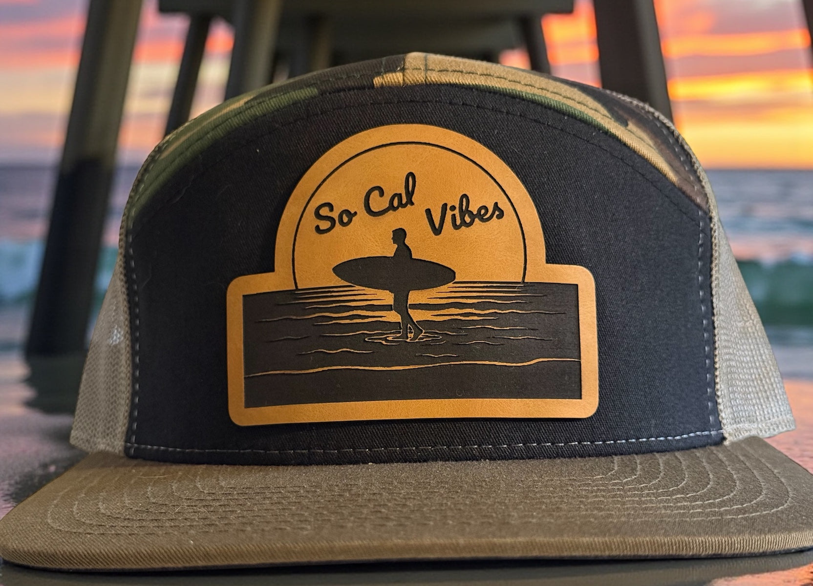 Custom trucker hat with 'So Cal Vibes' design featuring a surfer silhouette against a sunset, with a beach background