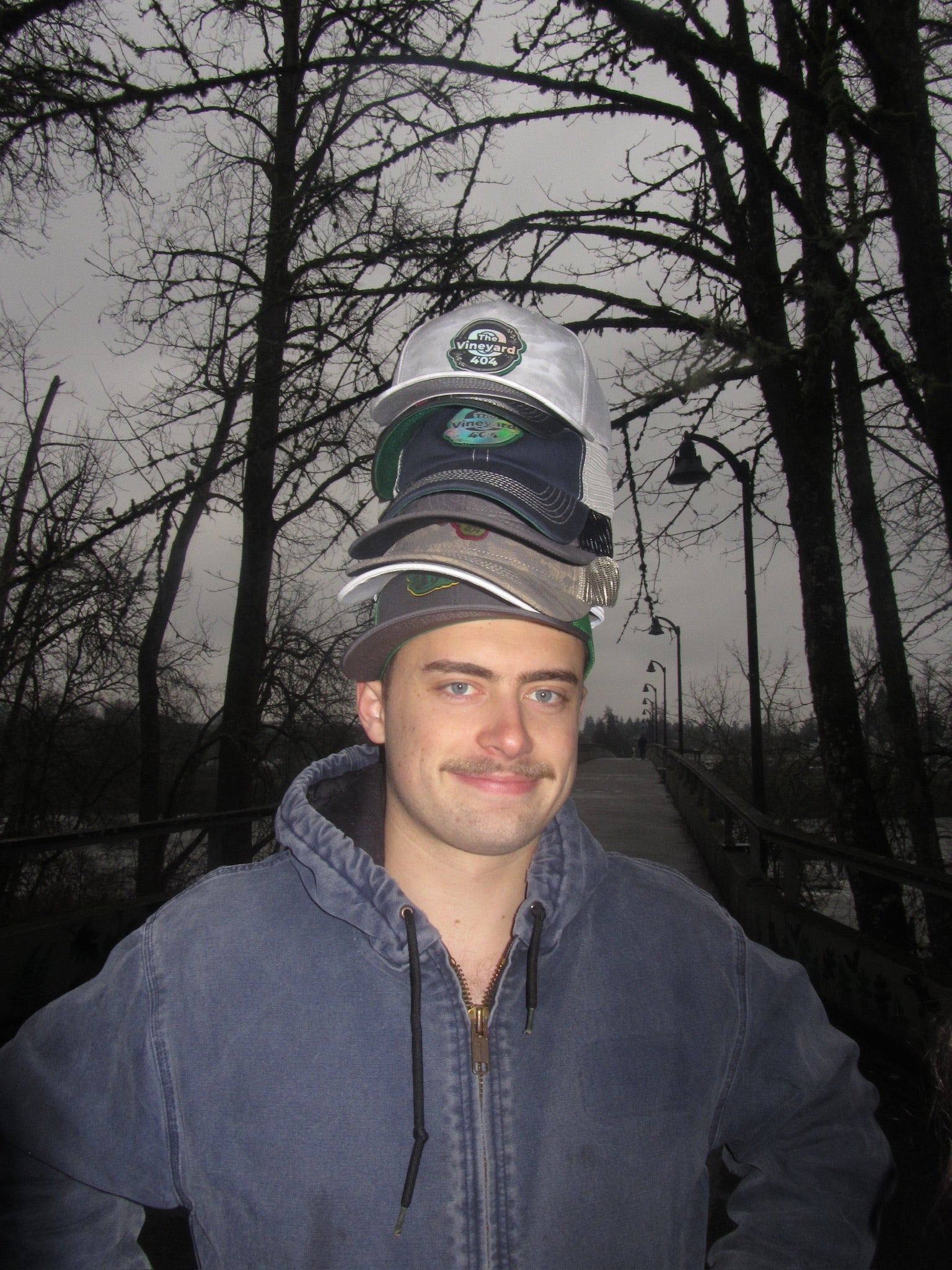 Man wearing multiple baseball caps stacked on his head